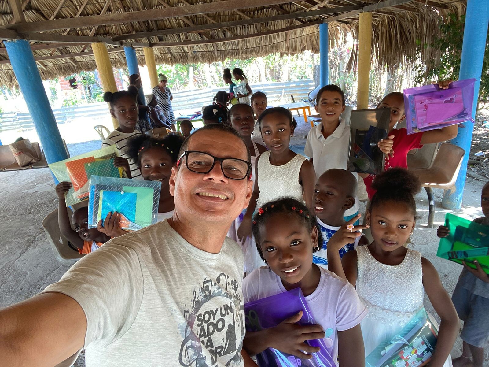 Niños mostrando sus trabajos escolares durante una jornada de educación bajo un pabellón