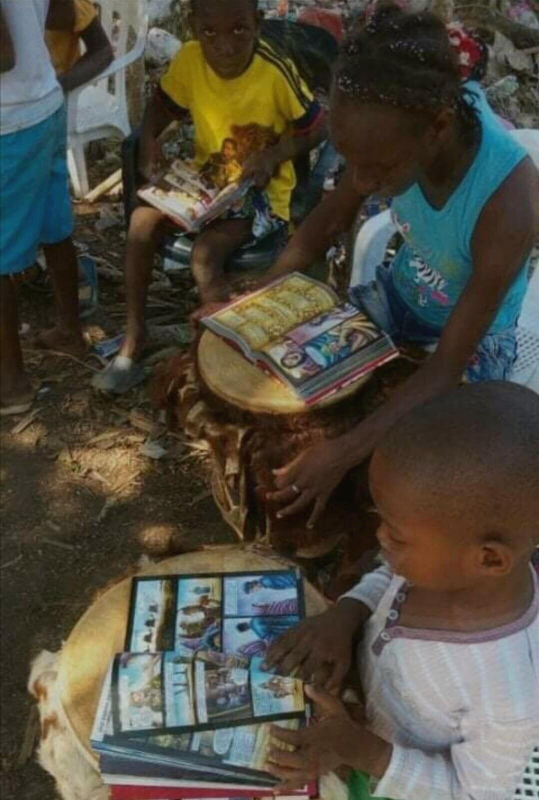 Niños leyendo biblias ilustradas apoyadas sobre tambores palenqueros