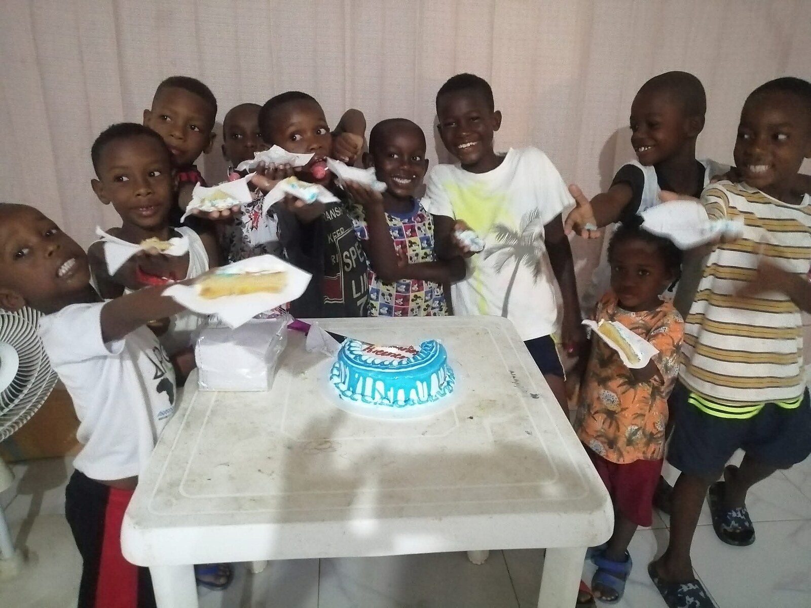 Niños sonrientes alrededor de una torta de celebración durante una jornada de la fundación